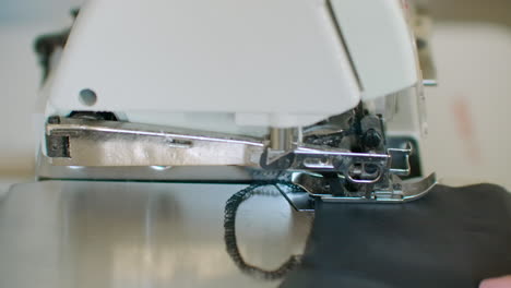 Close-up-the-overstitching-machine-passes-the-edges-of-the-black-fabric-in-slow-motion.-Serger-process-in-the-sewing-workshop